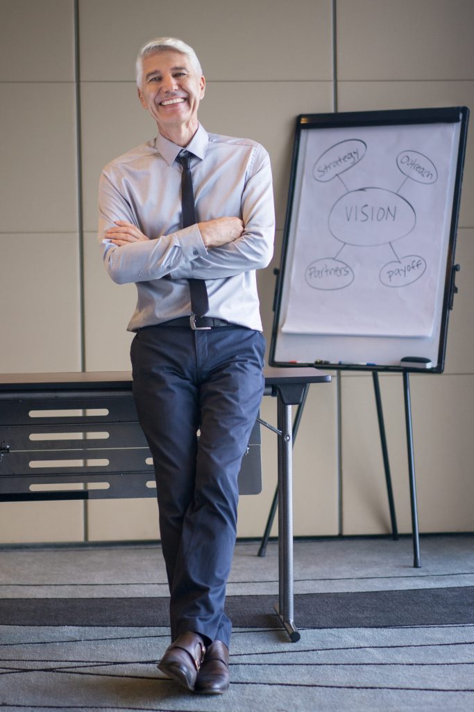 responsable d’entreprise souriant devant un tableau présentant la vision stratégique de l’entreprise